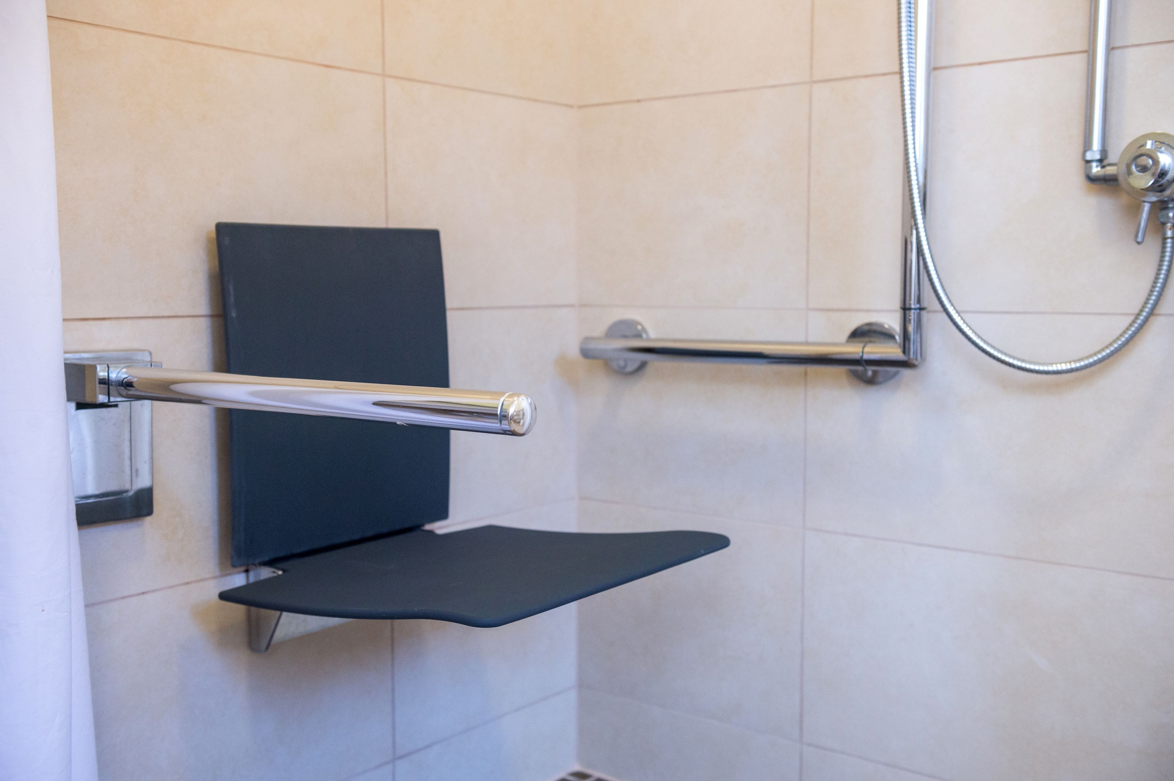 Une salle de bain moderne équipée d’une douche, d’un porte-serviettes et de toilettes avec un abattant noir.
