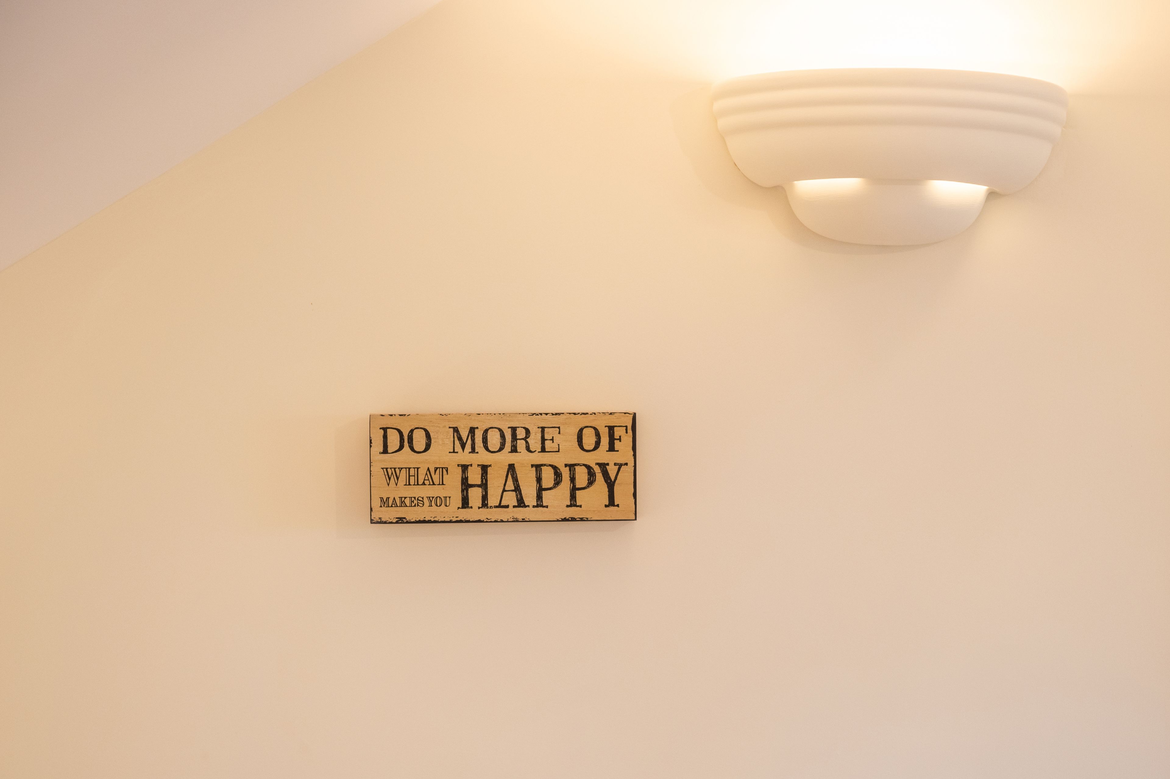 Un muro con un lampadario e un cartello con una frase motivazionale.