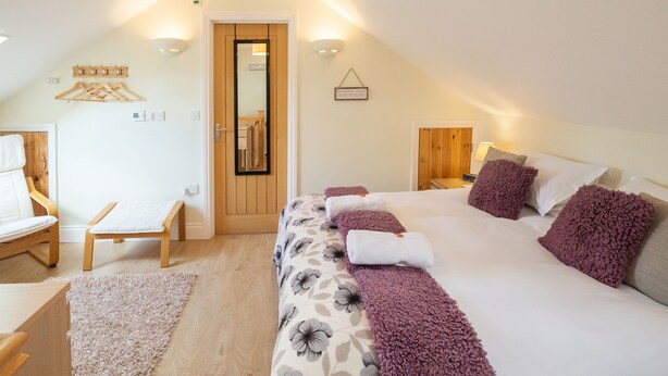 A bedroom with a bed, a bench, a chair, and a door. - Mollett's Farm (Saxmundham)
