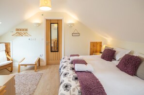 A bedroom with a bed, a bench, a chair, and a door. - Mollett's Farm (Saxmundham)