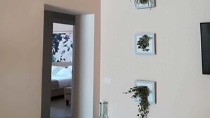 A hallway with a bed, a wall-mounted plant, a framed picture, and a clear glass bottle. - Villa Sece - Luxury Rooms (Agrigento)