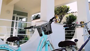 A turquoise bicycle parked in an outdoor area with a white building in the background. - Villa Sece - Luxury Rooms (Agrigento)