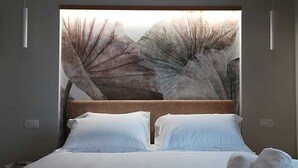A bedroom with a large bed, two pillows, a headboard, and a wall with a nature-themed artwork. - Villa Sece - Luxury Rooms (Agrigento)