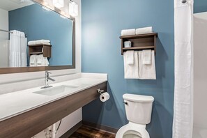 Ein Badezimmer mit einem weißen Waschbecken, einem Spiegel, einer Toilette und einem Handtuchhalter.