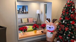 Un salon avec un grand miroir qui reflète un paysage urbain, un sapin de Noël et une décoration représentant un renne.
