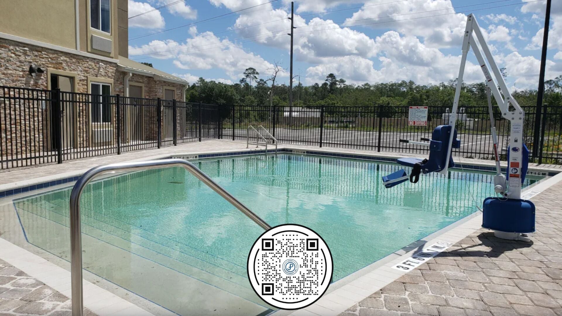 A swimming pool with a lifeguard stand, a metal pool ladder, and a QR code on the poolside.