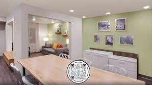 Une chambre d’hôtel moderne avec un coin repas, un canapé et des œuvres d’art accrochées aux murs.