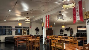 A restaurant interior with wooden tables and chairs, hanging decorations, and a Peruvian flag. - Tambo Lodge Canta (Canta)