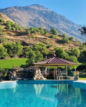A swimming pool with a gazebo, surrounded by a mountainous landscape. - Tambo Lodge Canta (Canta)