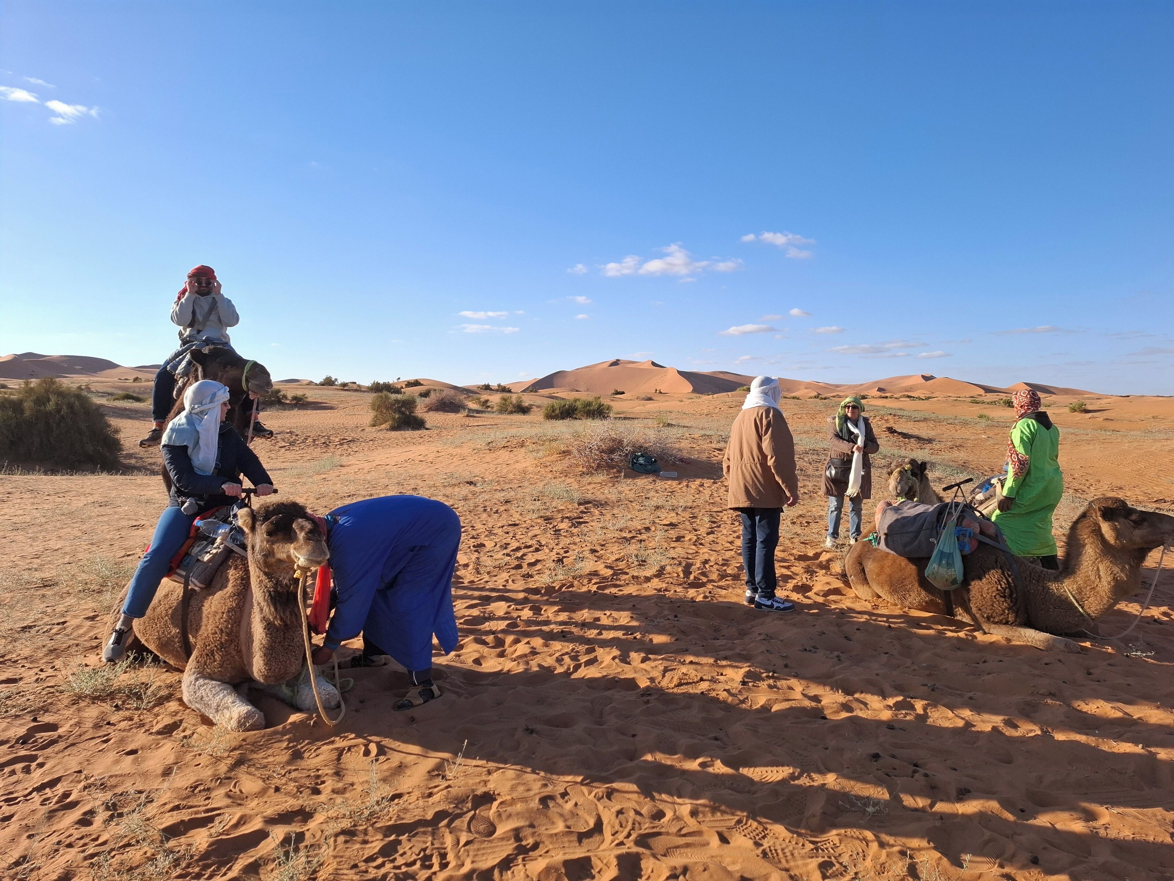 A desert landscape with people riding camels.