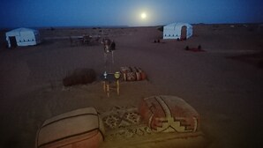 Een woestijnkamp met jurten, een tafel met stoelen en een tent.
