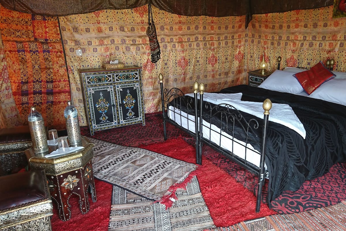 Une chambre de style traditionnel, avec un lit, des rideaux à motifs et un meuble décoratif.