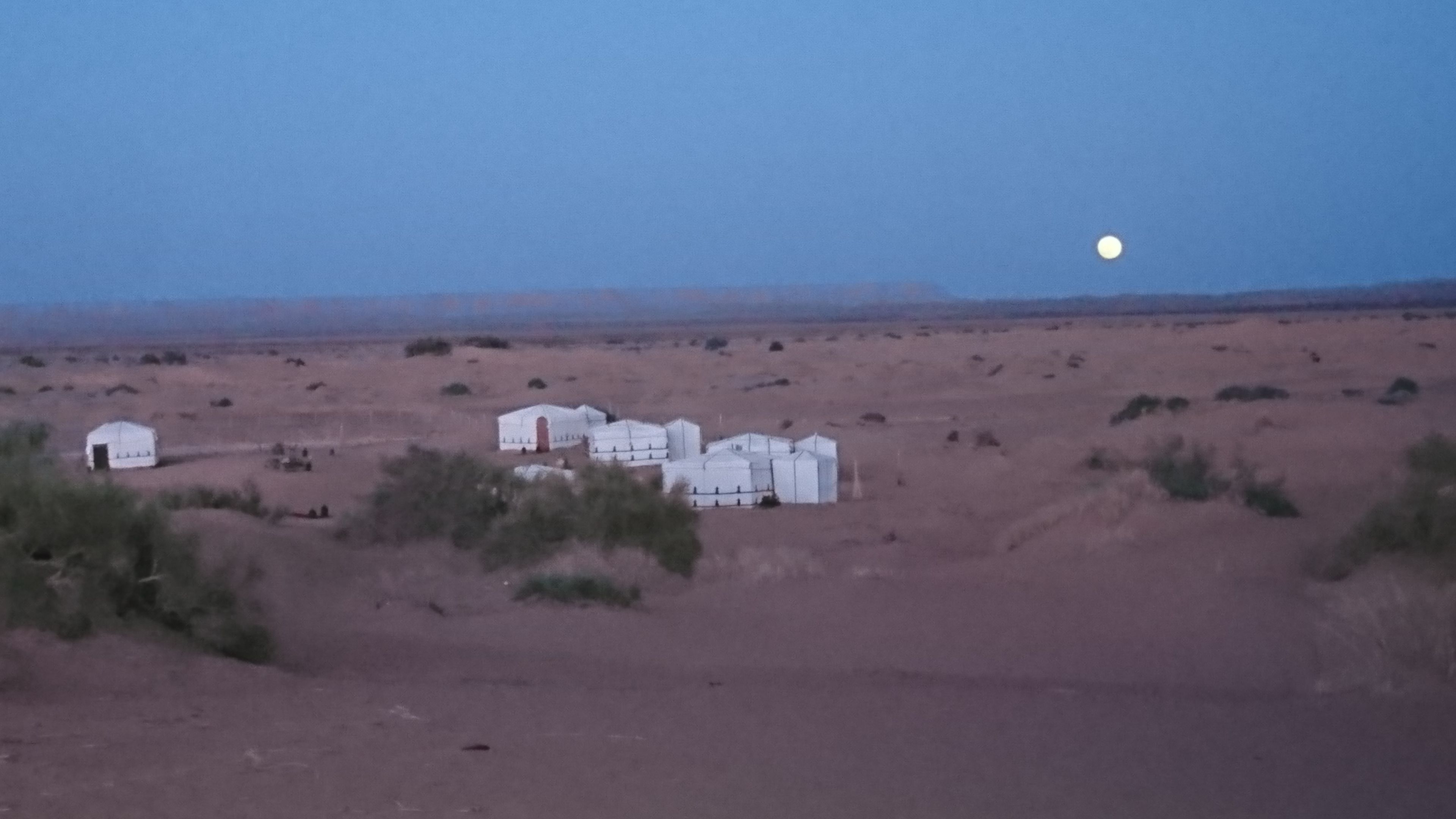 Paisaje desértico con varias tiendas blancas y un edificio grande y blanco.