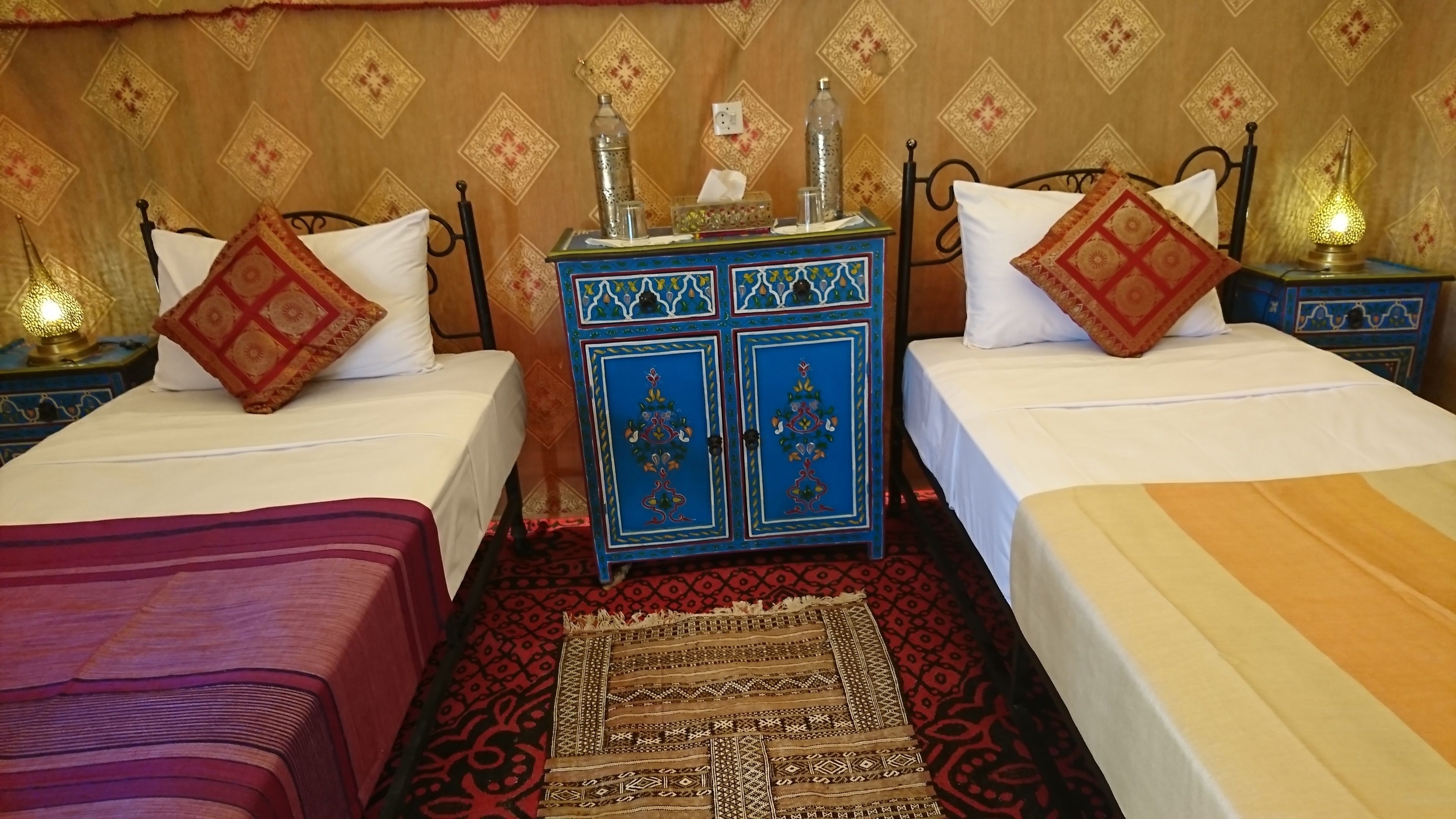 A room with two beds, a decorative cabinet, and bedside lamps.