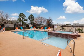 A rectangular swimming pool with a diving board, surrounded by lounge chairs and a fence. - Comfort Inn and Suites (Fredericksburg)