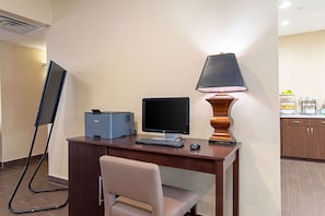 A hotel room with a desk, a computer, a lamp, a chair, and a flat-screen TV. - Comfort Inn and Suites (Fredericksburg)