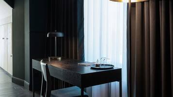 Een moderne kamer met een donker houten eettafel, twee stoelen, een vloerlamp en uitzicht door dunne gordijnen.