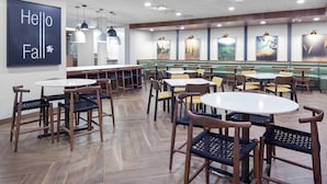 A restaurant with wooden flooring, multiple seating areas including tables and booths, and artwork on the walls. - Fairfield Inn & Suites by Marriott Fort Morgan (Fort Morgan)