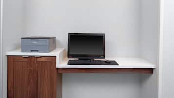 A computer setup on a desk with a printer, keyboard, and monitor.