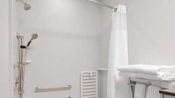 A modern bathroom with a shower, a towel rack, and a toilet paper holder.