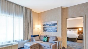 Habitación de hotel con sofá modular, una mesita, cama y un cuadro colgado en la pared.