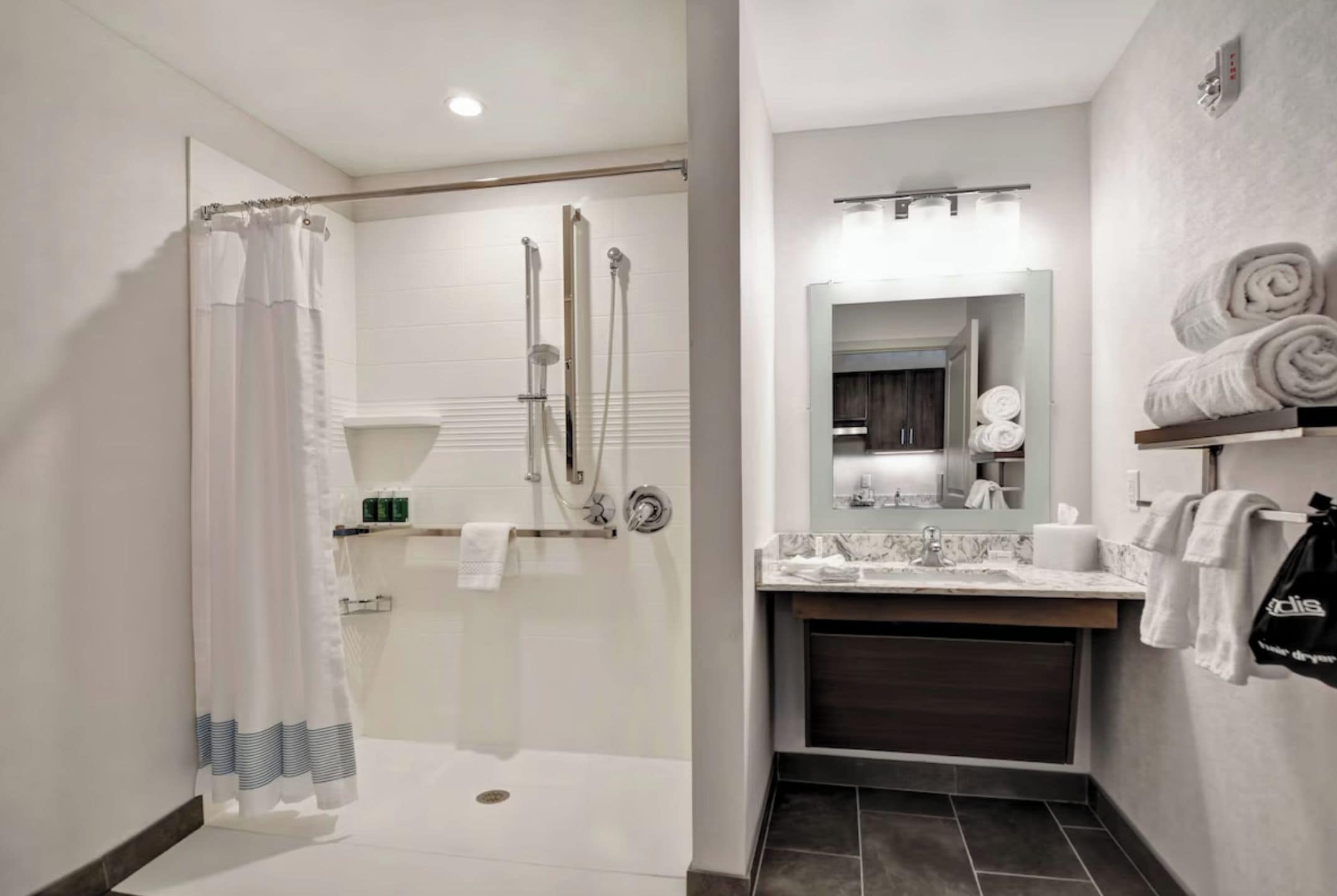 A modern bathroom with a walk-in shower, a vanity with a mirror, and a towel rack.