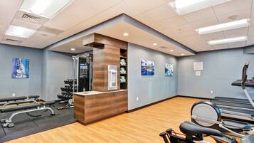A gym with exercise equipment, wooden flooring, and a reception desk.