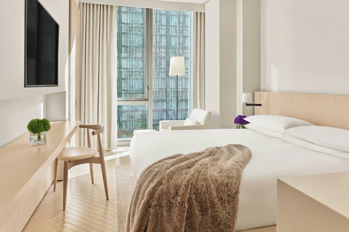Une chambre d’hôtel équipée d’un lit, d’un bureau, d’une chaise, d’une télévision et d’une fenêtre avec des rideaux.
