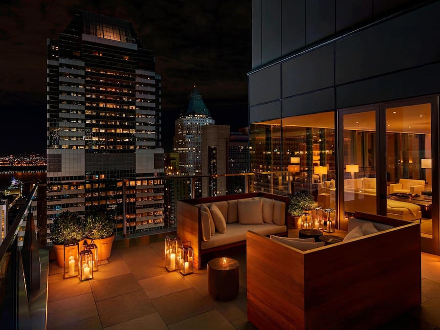A rooftop terrace with a sofa, potted plants, and candles.