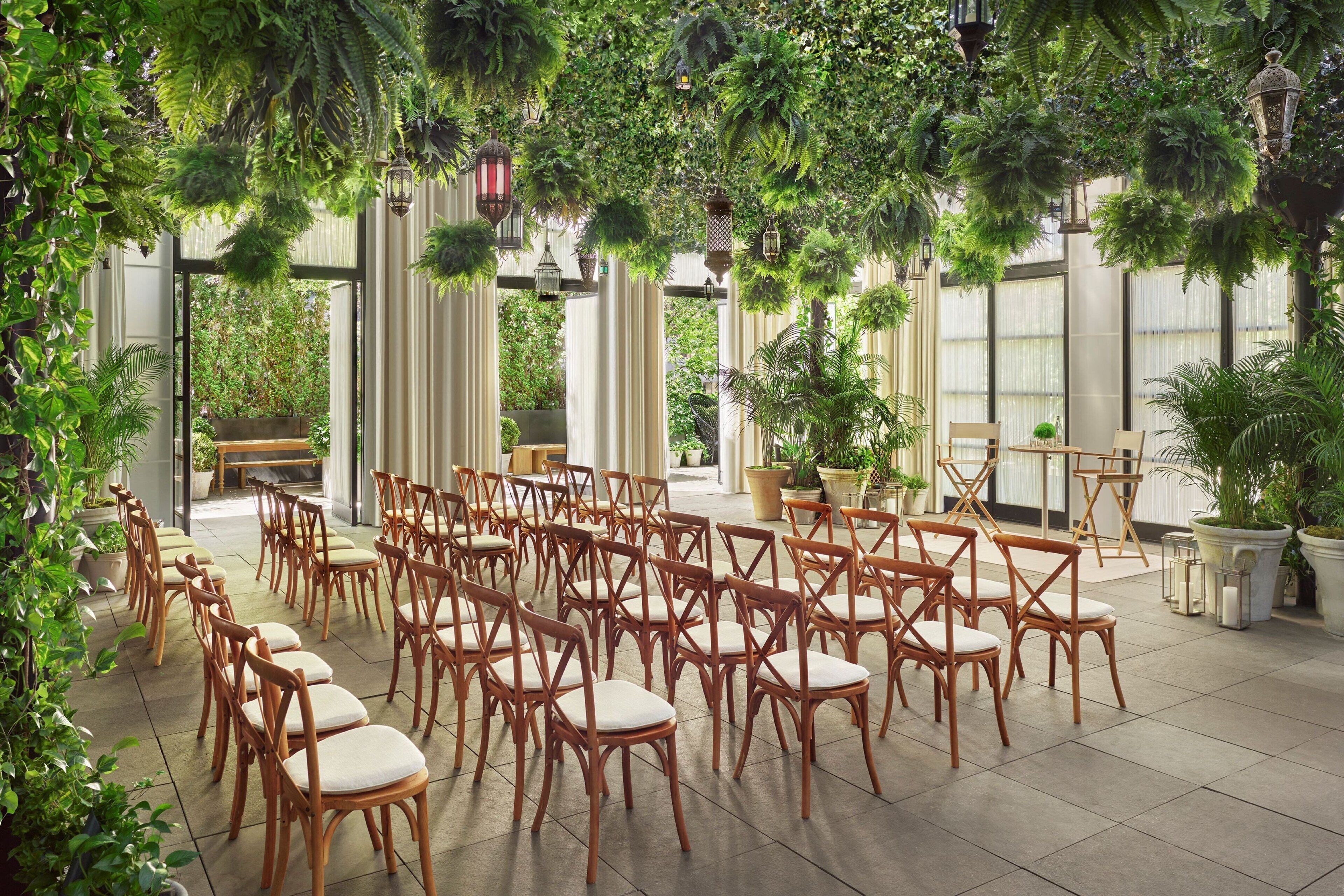 Un jardin intérieur avec des rangées de chaises en bois et des plantes en pot.