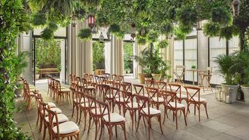 Un jardin intérieur avec des rangées de chaises en bois et des plantes en pot.
