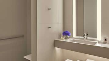Une salle de bain moderne avec un grand miroir, une douche et un meuble-lavabo doté d’un évier et d’un porte-serviettes.