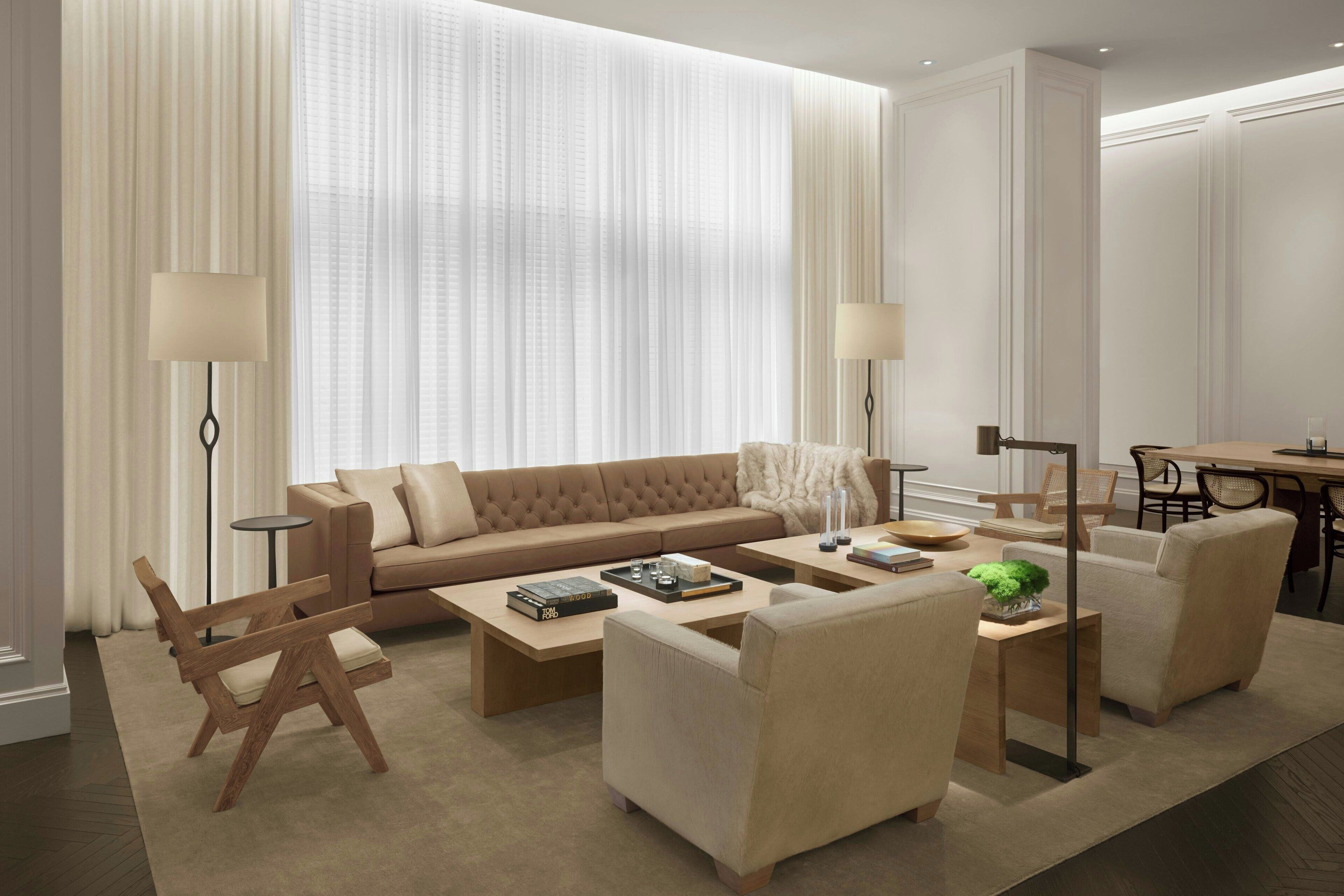 Un salon moderne avec un canapé beige, deux fauteuils, une table basse et un coin repas comprenant une table et des chaises.