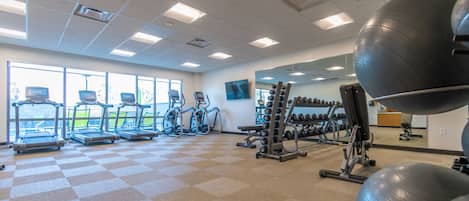 A gym with treadmills, elliptical machines, and free weights.
