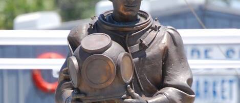 A statue of a person holding a helmet and a gas mask.