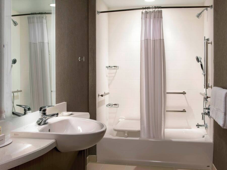 A modern bathroom with a sink, mirror, shower, and bathtub.