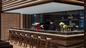 A modern bar area with a counter, bar stools, and a bartender. - Courtyard by Marriott Jiangsu Taizhou (Taizhou)