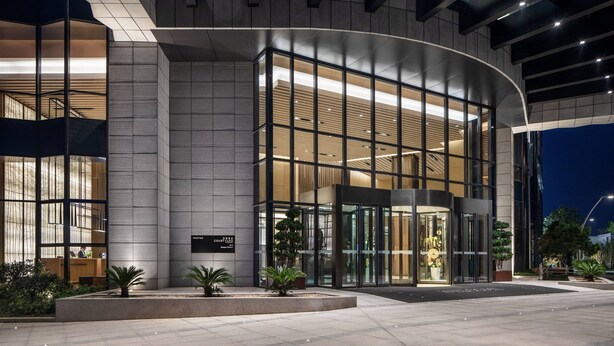 A modern hotel entrance with a curved facade, large glass windows, and a well-lit lobby area. - Courtyard by Marriott Jiangsu Taizhou (Taizhou)