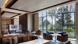 A modern hotel lobby with a large seating area, a reception desk, and large windows offering a view of the outdoors. - Courtyard by Marriott Jiangsu Taizhou (Taizhou)