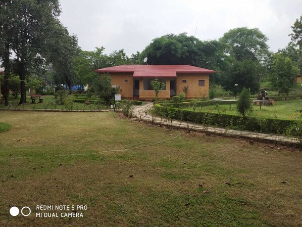 A building with a red roof, surrounded by a well-maintained lawn and trees.