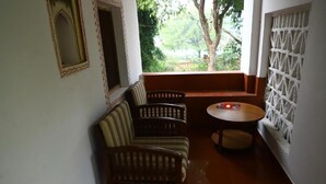 Ein kleiner, abgeschlossener Balkon mit einer hölzernen Bank, zwei Stühlen und einem runden Tisch.