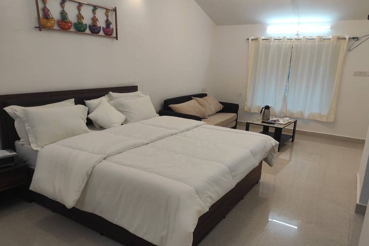 Une chambre à coucher avec un grand lit, une table de chevet, une chaise et une fenêtre avec des rideaux.