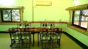 A dining area with a long table set for six, surrounded by chairs.