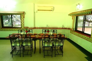 A dining area with a long table set for six, surrounded by chairs.