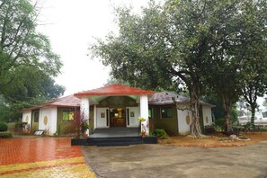 A building with a red roof and white walls, surrounded by trees.