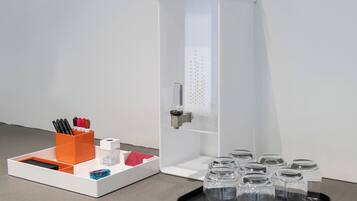 A white cabinet with a handle, a tray with pens and a red napkin, and several clear glass jars on a black tray.