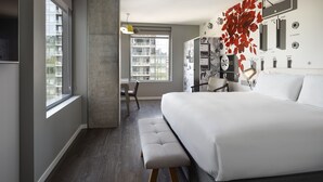 Une chambre moderne avec un grand lit, un banc, un bureau et une chaise.