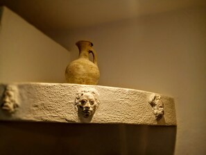 A stone shelf with a vase and two sculpted faces. - Agliastrello Rooms (Noto)