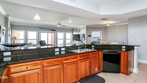 A spacious kitchen with granite countertops, wooden cabinets, and a dishwasher. - Gulf View Condo~ Paradise Shores 403 Sunset Paradise (Mexico Beach)