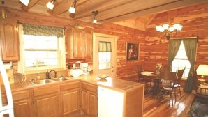 A log cabin interior with a kitchen, dining area, and a fireplace. - New red cedar log home just off the blue ridge parkway in Little Switzerland, NC (spruce pine)